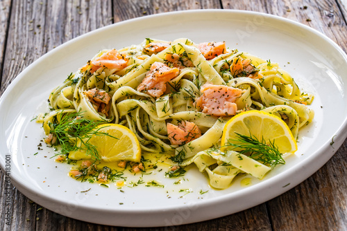 Tagliatelle with salmon and dill on wooden table 