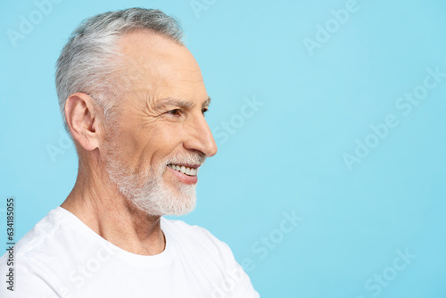 Elderly gray haired man wearing white t shirt isolated on blue background, copy space, face profile
