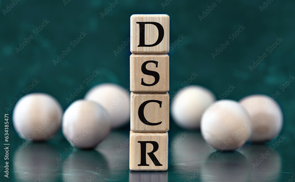 DSCR - acronym on wooden cubes on a green background with wooden balls DSCR - acronym on wooden cubes on a green background with wooden balls