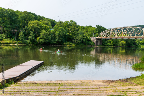 A man and woman heading out on the Allegheny River from the Tidioute Boat Ramp on kayaks in Tidioute, Pennsylvania, USA on a sunny summer day