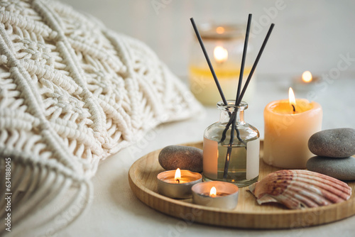 Burning candles on bamboo tray, cozy home atmosphere. Relaxation, detention zone in the living or bedroom. Stones, sea shells as decor. Apartment natural aroma diffusor with ocean breeze fragrance.
