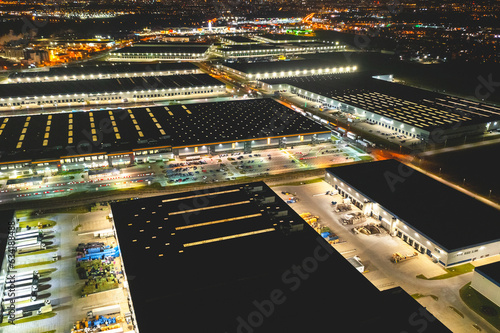 Aerial view of a warehouse of goods at night. Aerial view of industrial area, logistics warehouses and many trucks at night