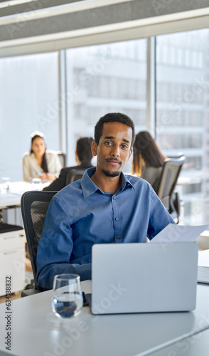 Young African American business man bank account manager sitting at office work holding documents. Ethnic businessman worker looking at camera at workplace, vertical portrait.