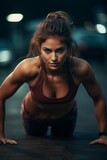 Young woman doing push-ups in the gym. Exercise, workout, body fitness. Go hard or go home. Dark background.