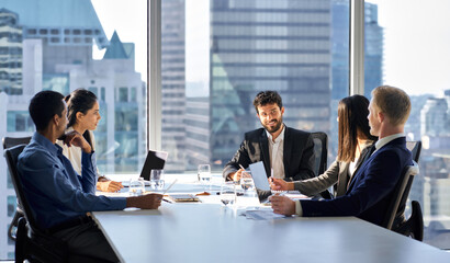 Happy international multiethnic professional business team, diverse executive colleagues people discussing financial project working together in office at group meeting table in corporate board room.