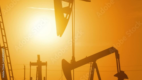 The sun rises behind a large oil field in California.