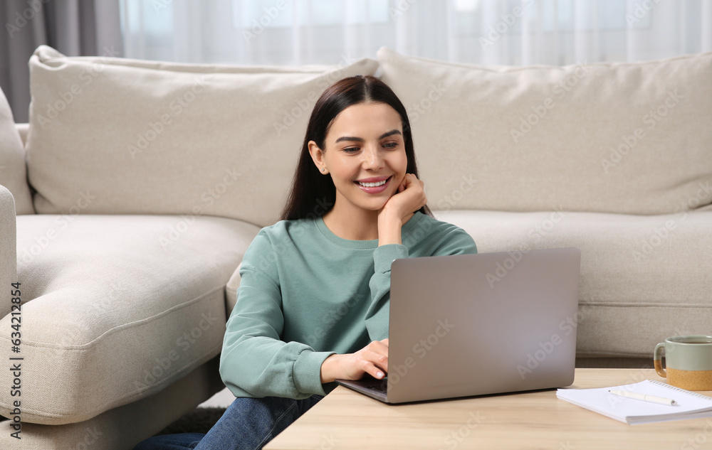 Happy woman working with laptop at coffee table in living room Happy woman working with laptop at coffee table in living room