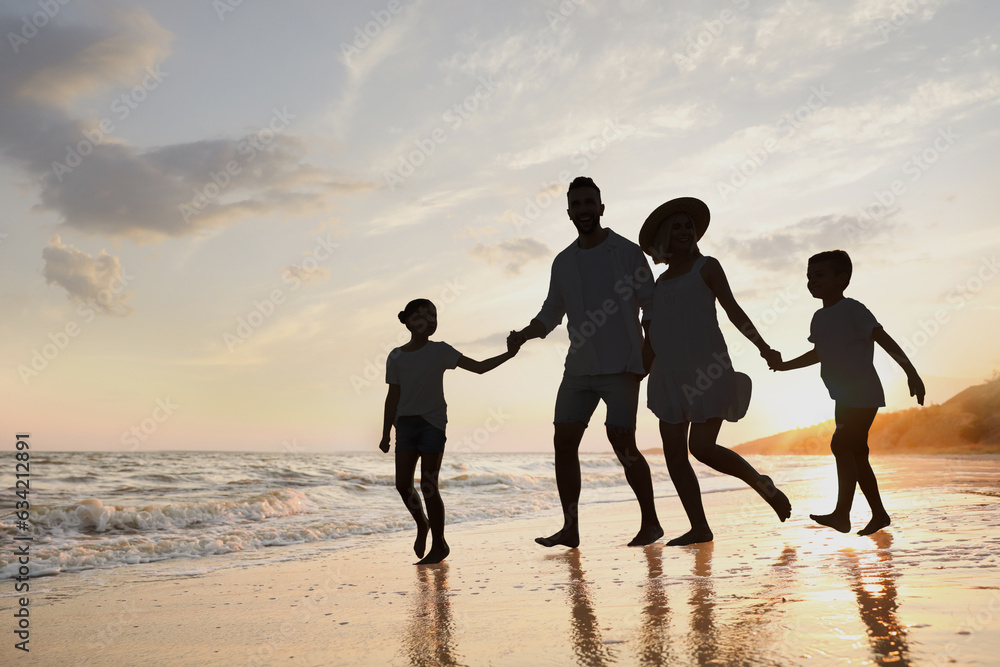 Fototapeta premium Silhouette of family on seashore at sunset