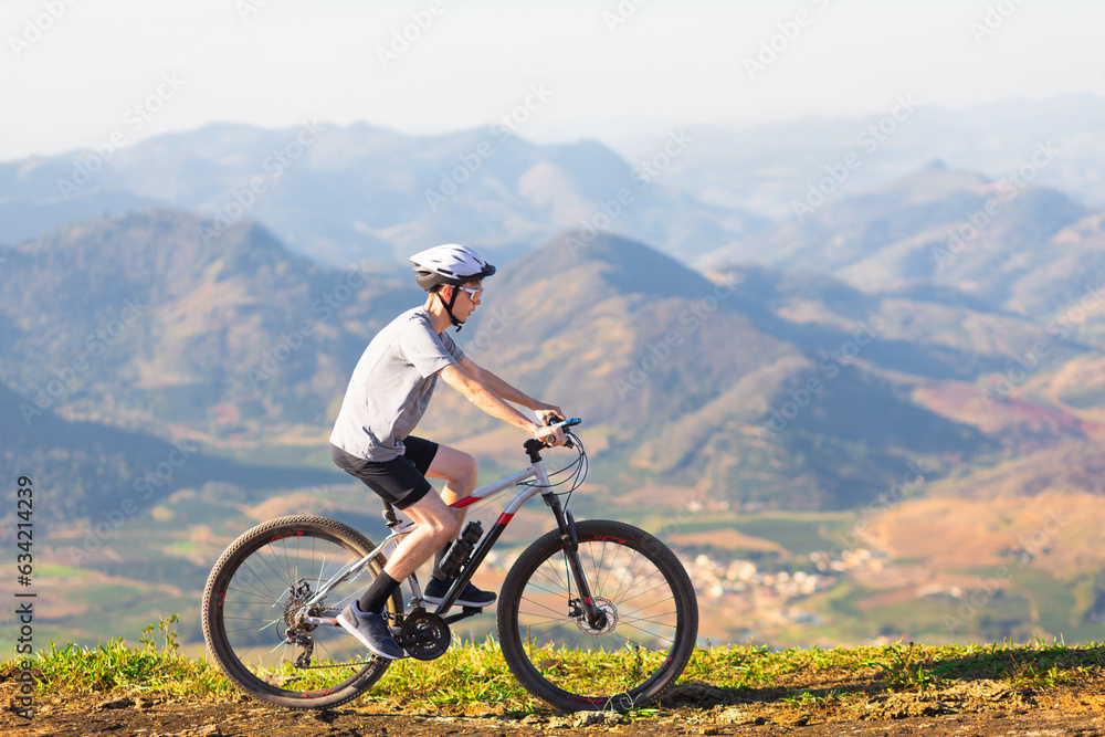 Cyclist riding a mountain bike down a trail with mountains in the background