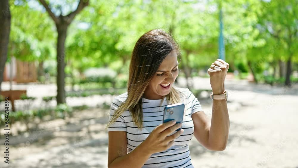 Middle eastern woman using smartphone with winner expression at park Middle eastern woman using smartphone with winner expression at park