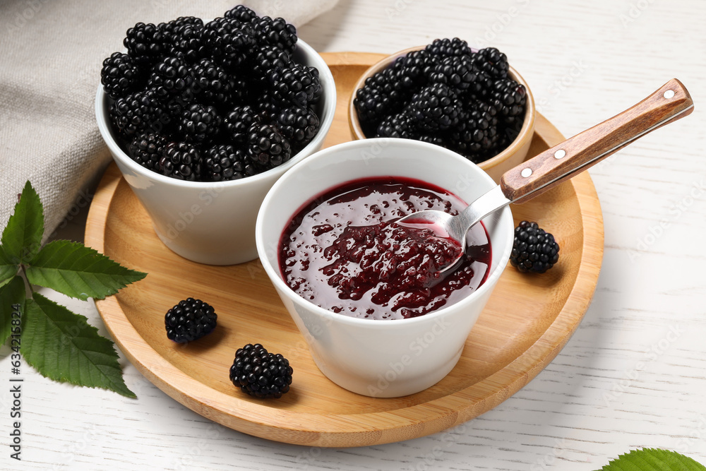 Fresh ripe blackberries, tasty jam and leaves on white wooden table, closeup Fresh ripe blackberries, tasty jam and leaves on white wooden table, closeup