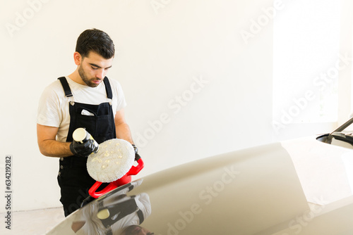 Professional worker using orbital polisher to polish car in the auto detail shop photo