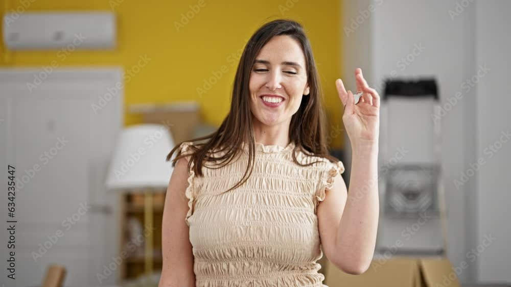 Young beautiful hispanic woman holding new house keys speaking at new home Young beautiful hispanic woman holding new house keys speaking at new home