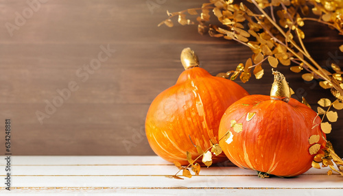 Orange halloween pumpkins with golden branches on brown. Happy Thanksgiving Day lush background. party decorationon white wooden deck or table. Selective focus on pumpkin. copy space wide banner photo