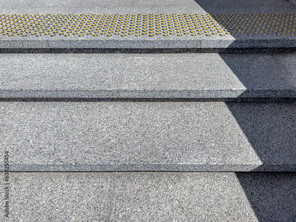 outdoors granite staircase with yellow nonskid bumpy markings on steps.
