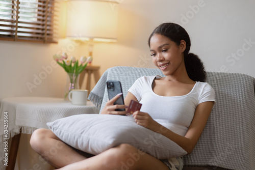Young African woman smartphone with credit card at home, Online Shopping.