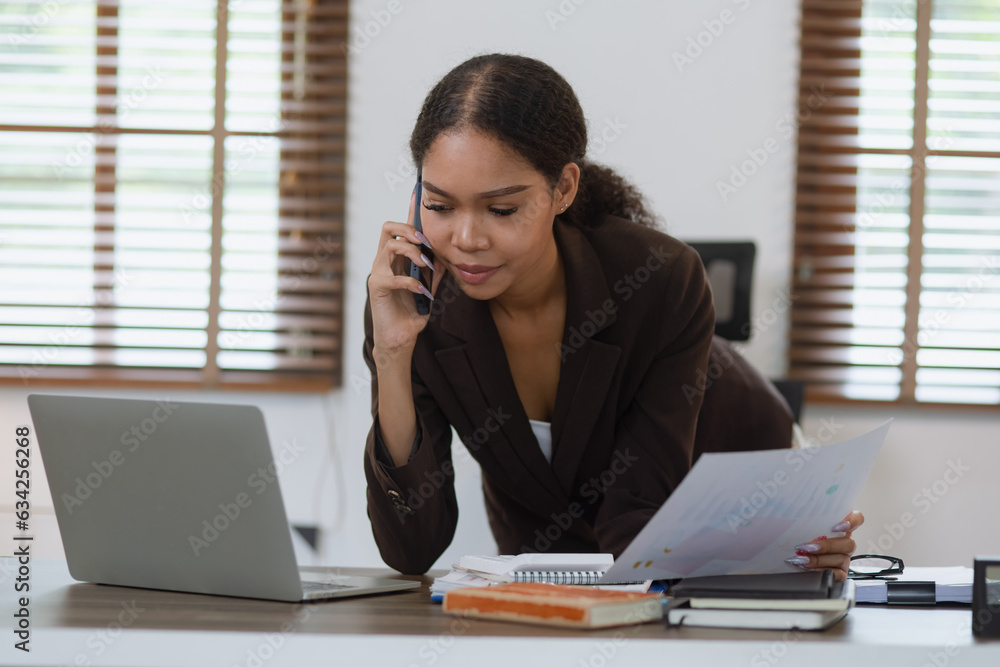 Young African woman using smartphone with laptop working at office, African American working online from home. Young African woman using smartphone with laptop working at office, African American working online from home.