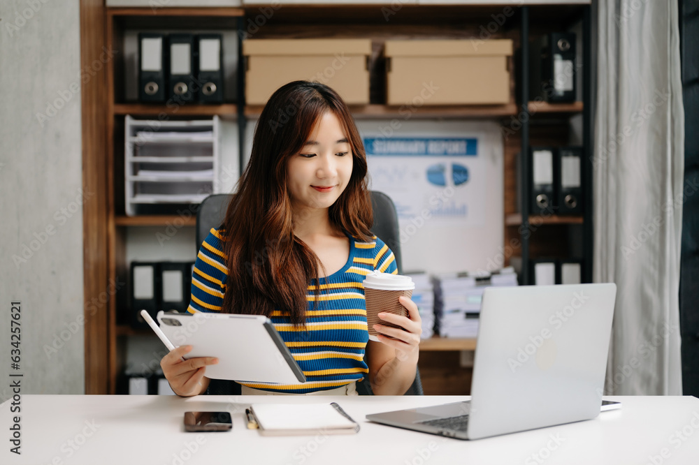 Confident Asian woman with a smile standing holding notepad and tablet at the modern office. Confident Asian woman with a smile standing holding notepad and tablet at the modern office.