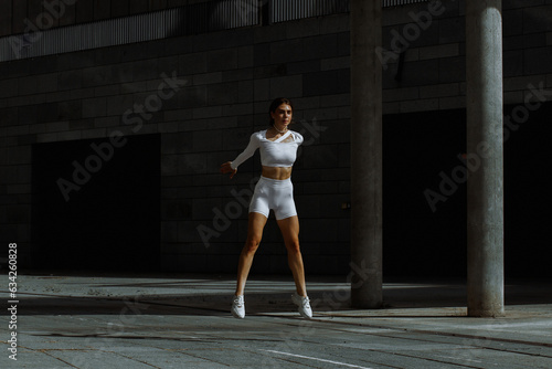 Sporty girl performs functional training on the street.