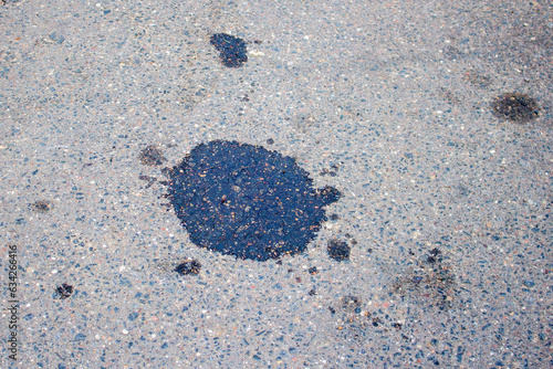 Dark wet oil spot on the asphalt surface at the street after a car