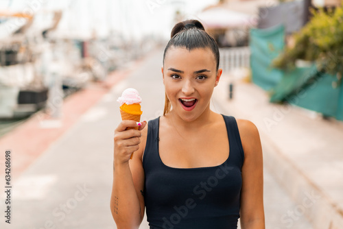 Young pretty woman with a cornet ice cream at outdoors with surprise and shocked facial expression