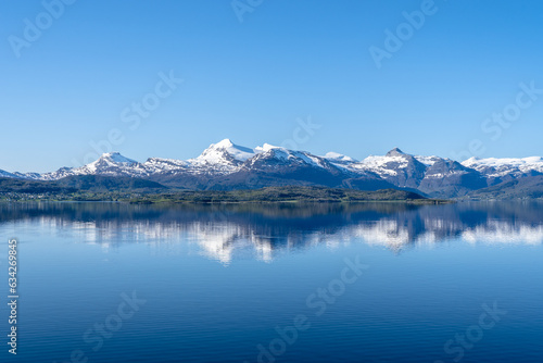 Snow covered fjords in Norway reflected in calm ocean © MODpix