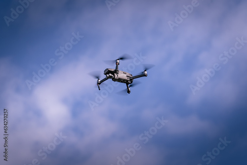 Drone flying in the blue sky with clouds. Flying drone.