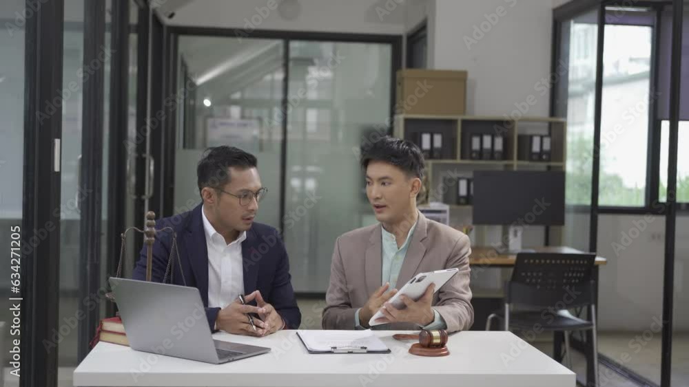 Meeting of two Asian male lawyers explaining legal situation, Asian man working in a b2b interview, network or law firm agreement. copyright infringement Meeting of two Asian male lawyers explaining legal situation, Asian man working in a b2b interview, network or law firm agreement. copyright infringement