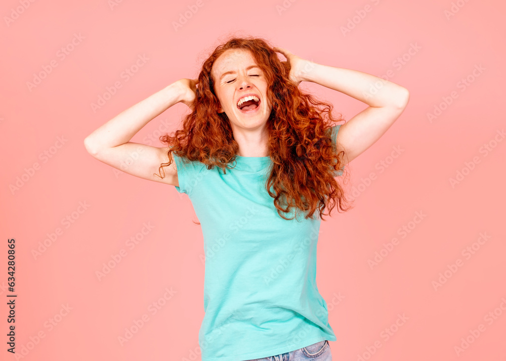 Screaming young red hair woman with curly wavy  hair  with closed ears in green t-shirt on pink background I’m done with everyone