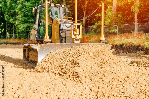 Roadworks and bulldozer levelling stone on top of geogrid plastic mesh