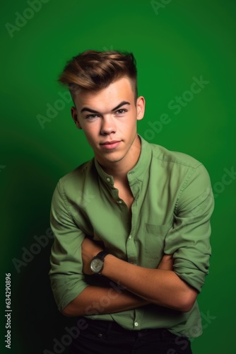 studio portrait of a stylish young man posing against a green background