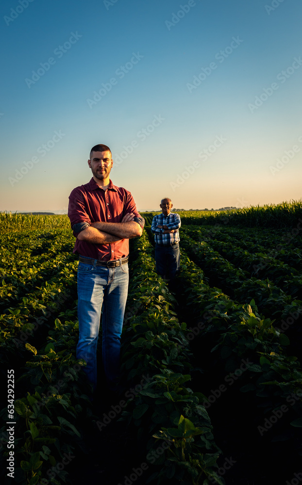 Portrait of two farmers standing in soy field looking at camera.