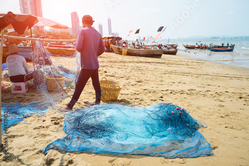 Foto Blue trawl that cone-shaped net through the sea at a deep level behind a special boat in order to catch fish with fishing boat and fisherman at the beach