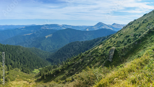 Mountain landscape in early autumn. Coniferous forest mountain valley. Steep slopes in the foreground