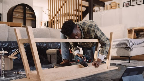A Black Man Screwing in a Screw into a Wooden DIY Table in the Lounge