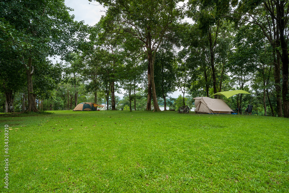 nature landscape camping or glamping cabin tent on green grass or lawn campground and tree for camper family holiday vacation on rainy season and cloudy at pom pee campsite in khao laem national park