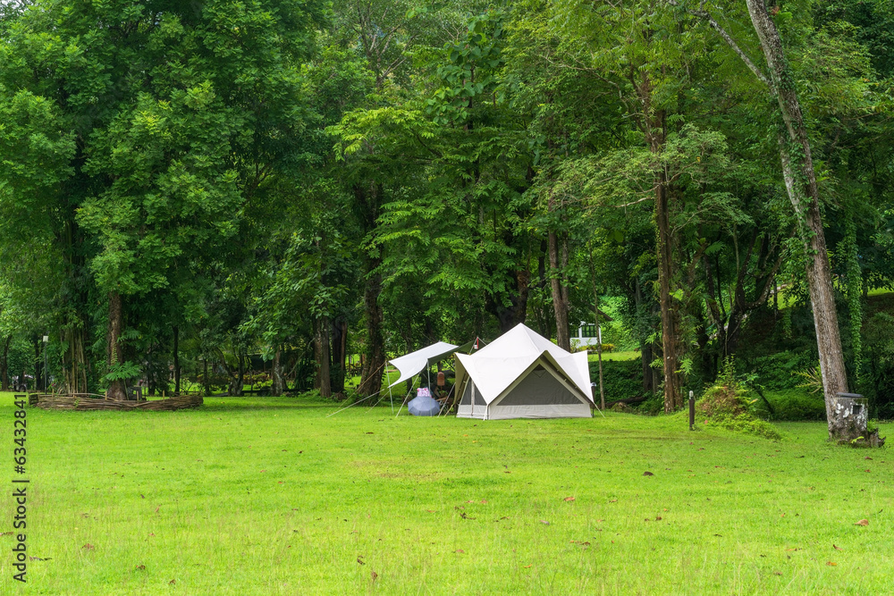 nature landscape camping or white glamping cabin tent on green grass lawn campground and tree for camper family holiday vacation on rainy season at khao laem national park in ka teng cheng waterfall - obrazy, fototapety, plakaty 