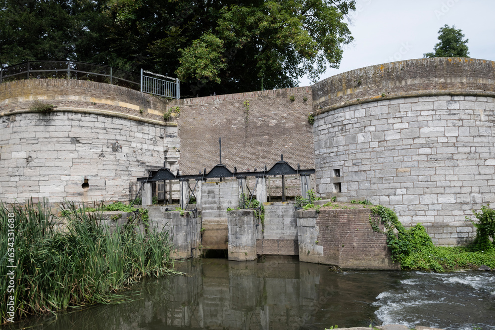 water gate Waterpoort De Reek Stadsmuur Maastricht, Netherlands. Fortified historic medieval city walls with river Jeker in monseigneur nolenspark park. Old town protective defence stone structure 