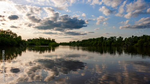Landscape of a cloudy sky near sunset reflected in the water of the Mississippi River with tree lined banks near Alton  IL