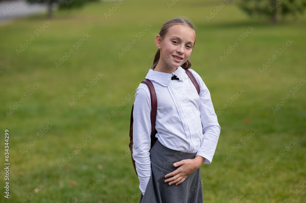 Caucasian girl in uniform and with a backpack goes from school. Caucasian girl in uniform and with a backpack goes from school.