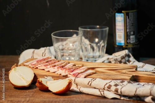 Raw pork fat, grated with salt and spices. Slicing meat on a wooden board surrounded by vegetables