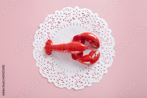 a red metal lobster on a white doily