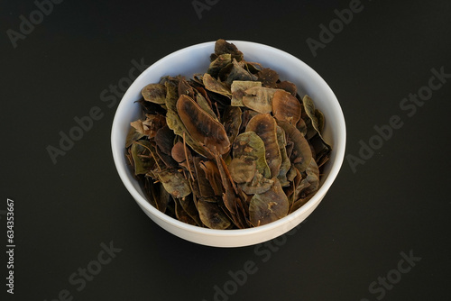 Heap of Senna alexandrina pods on a white plate on a black background photo