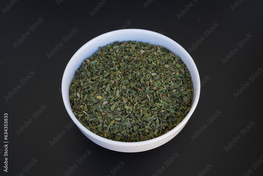 Dried mint in a white plate on a black background Dried mint in a white plate on a black background