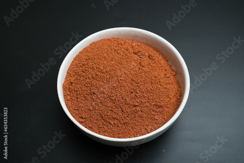Red chili powder on a white plate on a black background