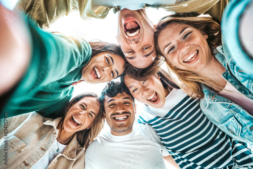 Multicultural group of young people smiling together at camera - Happy friends taking selfie pic with smartphone outdoors - Life style concept with guys and girls enjoying sunny day photo