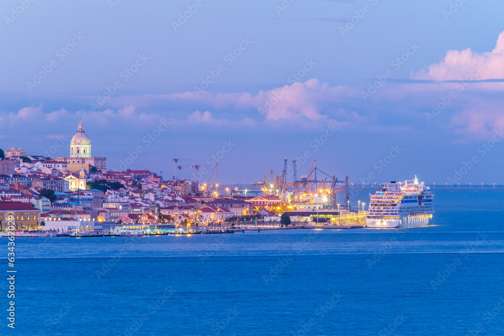 View of Lisbon over Tagus river with moored cruise liner in evening twilight. Lisbon, Portugal