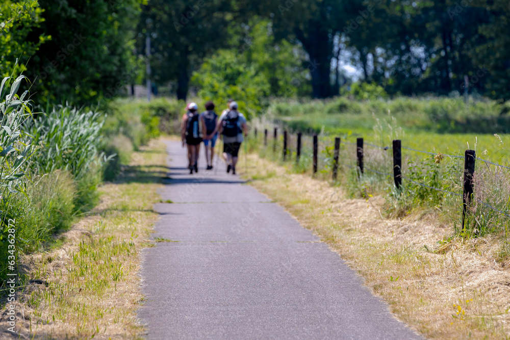Countryside road with blurred group of peoples hiking, The Pieterpad is a long distance walking route in the Netherlands, The trail runs from northern part of Groningen to end just south of Maastricht Countryside road with blurred group of peoples hiking, The Pieterpad is a long distance walking route in the Netherlands, The trail runs from northern part of Groningen to end just south of Maastricht