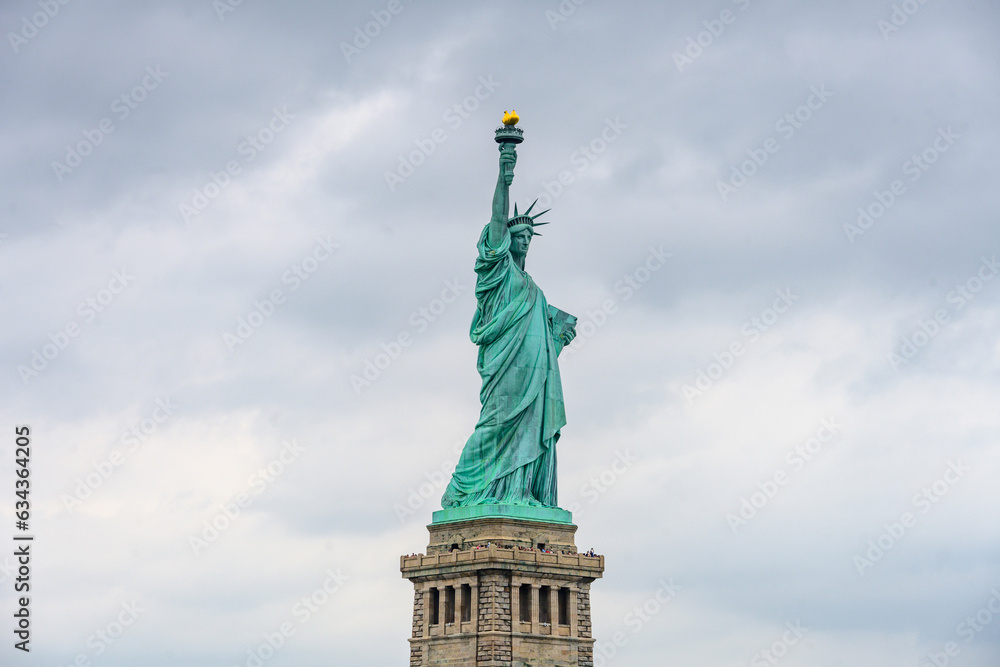 New York, New York, United States. August 07, 2023. Dramatic and detailed image of the Statue of Liberty with strong shades of green, sky with many clouds and very high resolution.