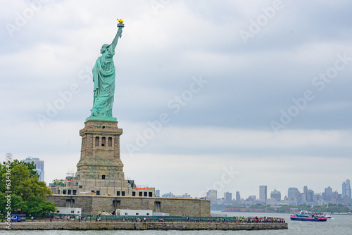 New York, New York, United States. August 07, 2023. Dramatic and detailed image of the Statue of Liberty with strong shades of green, sky with many clouds and very high resolution.